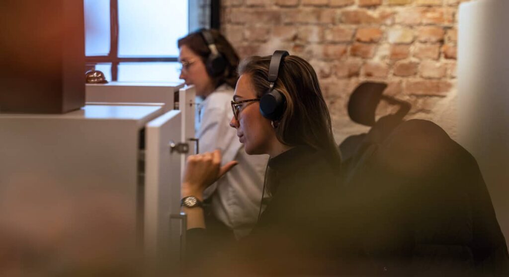 Two women with headphones looking at computers
